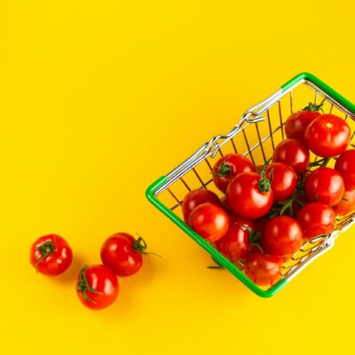 노란 배경 위 초록 장바구니에 담긴 방울토마토